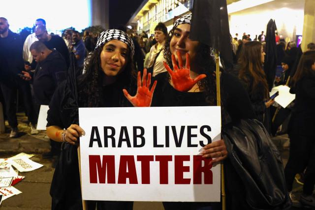 Protesters hold a placard and show their paint-covered hands during a demonstration against rising crime rates against Arab-Israelis in Tel Aviv on January 31, 2026. (Photo by AHMAD GHARABLI / AFP)