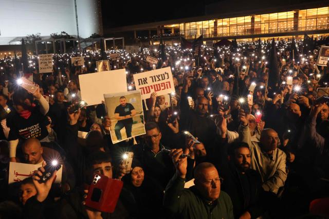 People hold placards and light their phone torches during a demonstration against rising crime rates against Arab-Israelis in Tel Aviv on January 31, 2026. (Photo by AHMAD GHARABLI / AFP)
