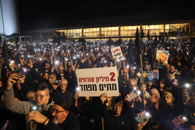 People hold placards and light their phone torches during a demonstration against rising crime rates against Arab-Israelis in Tel Aviv on January 31, 2026. (Photo by AHMAD GHARABLI / AFP)