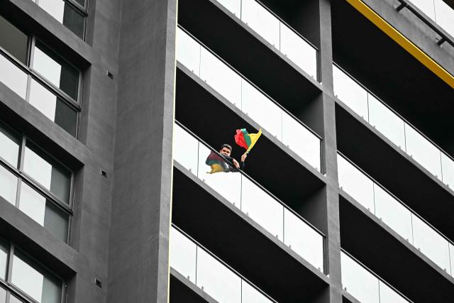 A supporter of Costa Rican presidential candidate Claudia Dobles waves a flag in the party's colors from his balcony in San Jose on January 31, 2026, the day before the presidential election. (Photo by Marvin RECINOS / AFP)
