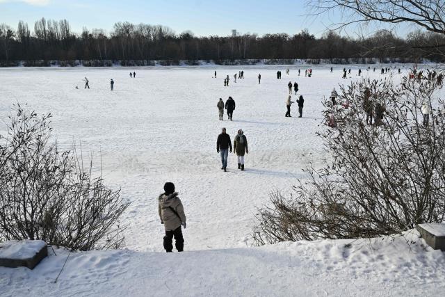 People walk on the frozen Dnipro River in a residential neighborhood of Kyiv, on January 31, 2026, during mass power outages amid the Russian invasion of Ukraine. (Photo by Genya SAVILOV / AFP)