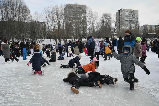 Children play on the ice during an outdoor party on a side of the frozen Dnipro River in a residential neighbourhood of Kyiv, on January 31, 2026, to lift spirits during mass power outages amid the Russian invasion of Ukraine. (Photo by Genya SAVILOV / AFP)