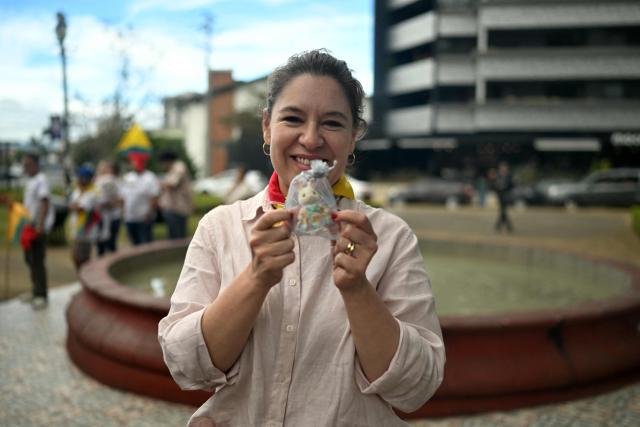 Costa Rica's presidential candidate of the Citizen Agenda Coalition and former first lady, Claudia Dobles, shows a gift given to her by a supporter during a gathering in San Jose on January 31, 2026, the day before the presidential election. (Photo by MARVIN RECINOS / AFP)
