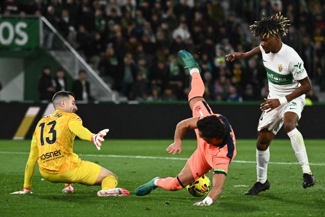 Barcelona's Spanish forward #07 Ferran Torres (C) falls down to the ground next to Elche's Spanish defender #18 John Donald and Elche's Spanish goalkeeper #13 Inaki Pena during the Spanish league football match between Elche CF and FC Barcelona at thge Martinez Valero stadium in Elche on January 31, 2026. (Photo by JOSE JORDAN / AFP)