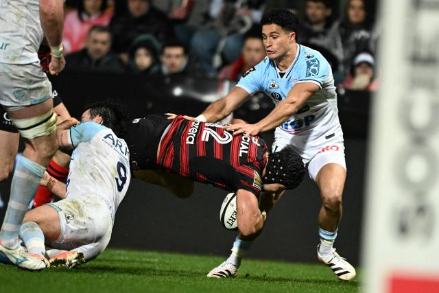 Toulouse's Argentinian centre Santiago Chocobares (C) is tackled by Bayonne's French scrum-half Baptiste Germain (L) during the French Top14 rugby union match between Stade Toulousain Rugby (Toulouse) and Aviron Bayonnais (Bayonne) at the Ernest-Wallon stadium in Toulouse, south-western France on January 31, 2026. (Photo by Lionel BONAVENTURE / AFP)