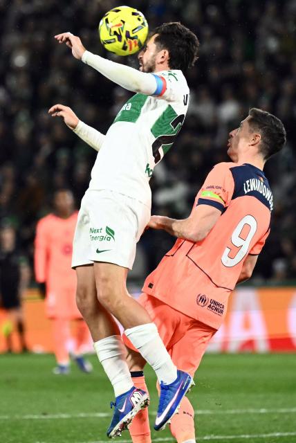 Elche's Spanish defender #23 Victor Chust wins a header over Barcelona's Polish forward #09 Robert Lewandowski during the Spanish league football match between Elche CF and FC Barcelona at thge Martinez Valero stadium in Elche on January 31, 2026. (Photo by JOSE JORDAN / AFP)