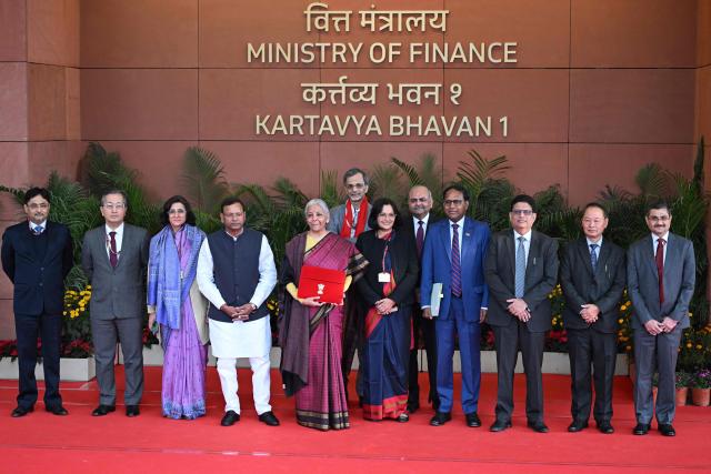 India's Finance Minister Nirmala Sitharaman (5th L) poses for photos as she leaves the Finance Ministry to present the annual budget to parliament at the Kartavya Bhavan in New Delhi on February 1, 2026. (Photo by Sajjad HUSSAIN / AFP)