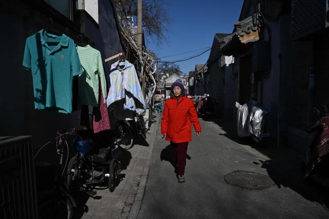 A woman walks through an alley in a hutong neighbourhood in Beijing on February 1, 2026. (Photo by Pedro PARDO / AFP)