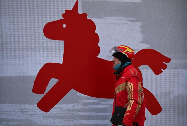 A delivery person walks past a store decoration ahead of the Lunar New Year of the Horse in Beijing on February 1, 2026. (Photo by Pedro PARDO / AFP)