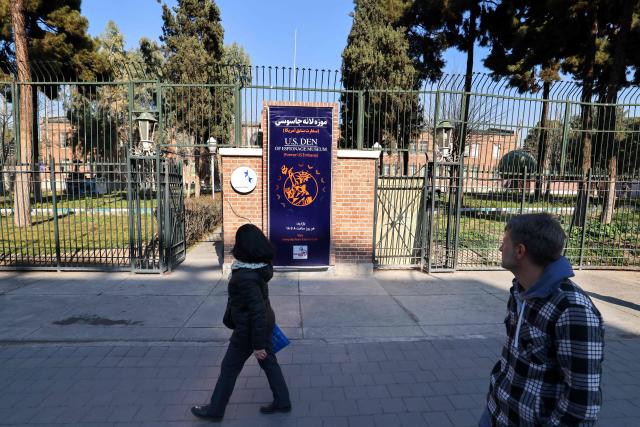 People walk outside the former US embassy in Tehran, colloquially-referred to as the "Spy Den,"on February 1, 2026. Iran's supreme leader Ayatollah Ali Khamenei warned on February 1 of a "regional war" if the United States attacked following heavy military deployments by Washington in the Gulf. (Photo by ATTA KENARE / AFP)