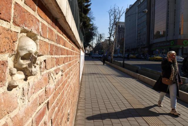 A woman walks outside the former US embassy in Tehran, colloquially-referred to as the "Spy Den,"on February 1, 2026. Iran's supreme leader Ayatollah Ali Khamenei warned on February 1 of a "regional war" if the United States attacked following heavy military deployments by Washington in the Gulf. (Photo by ATTA KENARE / AFP)