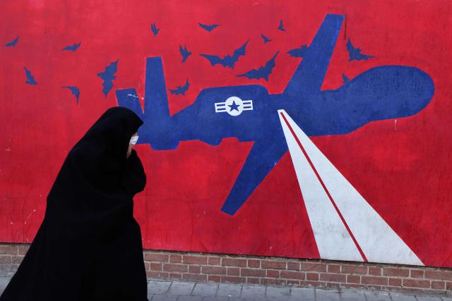 A woman walks past a mural depicting a US drone painted on the outer walls of the former US embassy in Tehran, colloquially-referred to as the "Spy Den,"on February 1, 2026. Iran's supreme leader Ayatollah Ali Khamenei warned on February 1 of a "regional war" if the United States attacked following heavy military deployments by Washington in the Gulf. (Photo by ATTA KENARE / AFP)