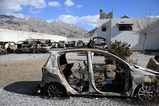 A man stands beside burnt vehicles inside a torched police station on the outskirts of Quetta on February 1, 2026 a day after an attack by Baloch separatists. Pakistan forces were hunting on February 1 for the separatists behind a string of coordinated attacks in the restive Balochistan province, with the government vowing to retaliate after more than 190 people were killed in two days. (Photo by Banaras KHAN / AFP)