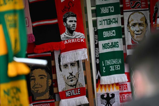 Scarves, including one of Manchester United's English Interim head coach Michael Carrick, are seen for sale on a merchandise stall outside the ground ahead of the English Premier League football match between Manchester United and Fulham at Old Trafford in Manchester, north west England, on February 1, 2026. (Photo by Paul ELLIS / AFP)