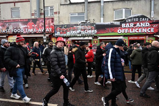 Arriving Manchester United fans pass fast food outlets outside the ground ahead of the English Premier League football match between Manchester United and Fulham at Old Trafford in Manchester, north west England, on February 1, 2026. (Photo by Paul ELLIS / AFP)