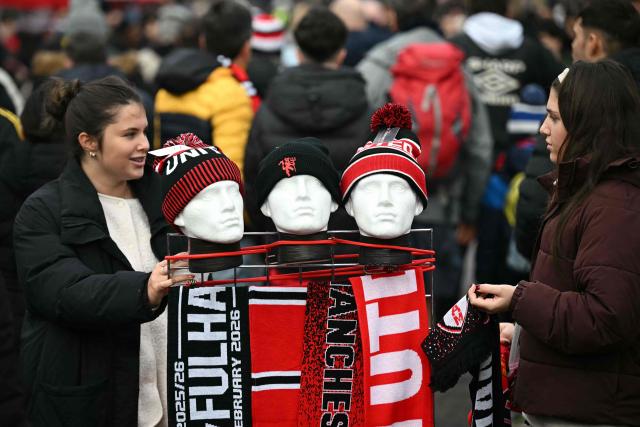 Merchandise sellers work outside the ground ahead of the English Premier League football match between Manchester United and Fulham at Old Trafford in Manchester, north west England, on February 1, 2026. (Photo by Paul ELLIS / AFP)