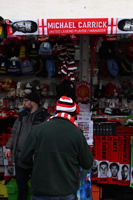 Scarves, including one of Manchester United's English Interim head coach Michael Carrick, are seen for sale on a merchandise stall outside the ground ahead of the English Premier League football match between Manchester United and Fulham at Old Trafford in Manchester, north west England, on February 1, 2026. (Photo by Paul ELLIS / AFP)