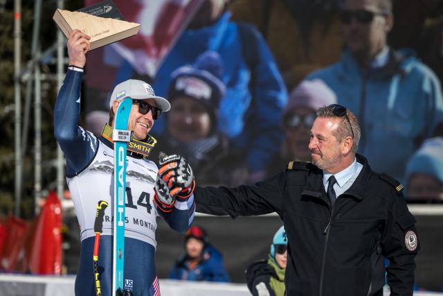 Crans-Montana’s Fire chief David Vocat (R) congratulates third-placed US Ryan Cochran-Siegle (L) as he celebrates on the podium after competing in the men's downhill race part of the FIS Alpine Ski World Cup 2025-2026, in Crans Montana, Switzerland, on February 1, 2026. (Photo by Fabrice COFFRINI / AFP)