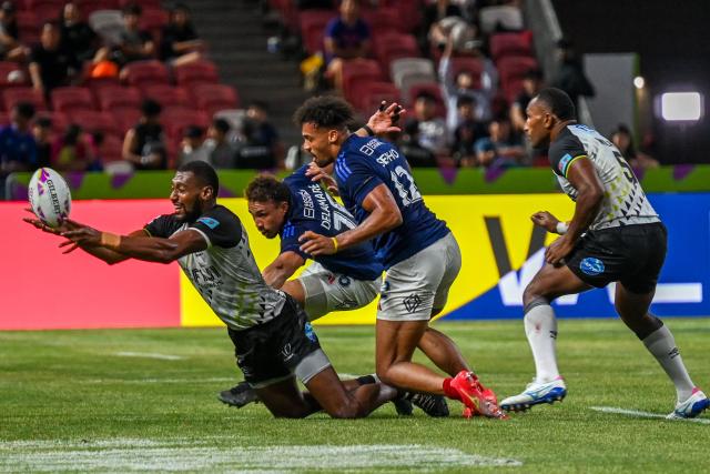 Fiji's Joseva Talacolo (L) fights for the ball against team France at the men's final event during the HSBC Rugby Sevens Singapore tournament in the National Stadium, Singapore on February 1, 2026. (Photo by Roslan RAHMAN / AFP)