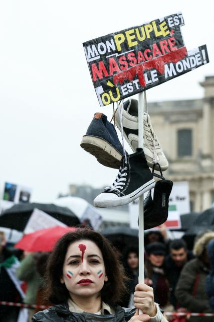 A protester with her face painted in red and with the colour of the Iranian flag, holds a placard reading "My people are being massacred, where is the world?" as she takes part in a March for Iran in support of the Iranian people, called by pro-royalists and supporters of the son of the last shah of Iran Mohammad Reza Pahlavi, on Place Vauban, in Paris on February 1, 2026. (Photo by Alain JOCARD / AFP)