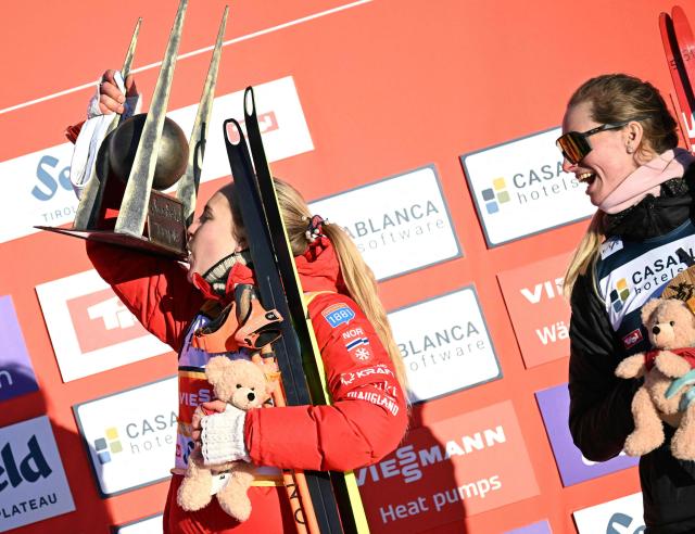 Winner Norway's Ida Marie Hagen (L) kisses her trophy as third placed US' Tara Geraghty-Moats looks on as they celebrate on the podium after the Women's Individual Gundersen Norman Hill HS109/7,5km event of the FIS Nordic Combined World Cup in Seefeld, Austria, on February 1, 2026. (Photo by BARBARA GINDL / APA / AFP) / Austria OUT