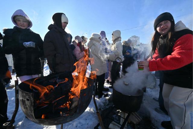 A volunteer distributes hot drinks to attendees of an outdoor DJ party in a one of a residential neighbourhood of Kyiv,  to lift spirits during mass power outages and central heating, on February 1, 2026 amid the Russian invasion of Ukraine. (Photo by Sergei SUPINSKY / AFP)