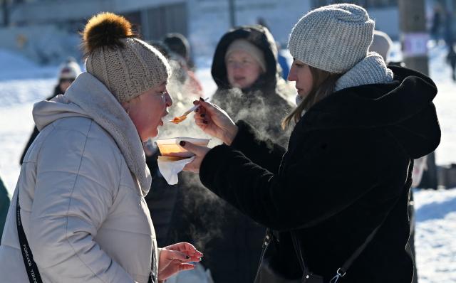 Residents eat hot soup during an outdoor DJ party in a one of a residential neighbourhood of Kyiv, to lift spirits during mass power outages and central heating on February 1, 2026 amid the Russian invasion of Ukraine. (Photo by Sergei SUPINSKY / AFP)