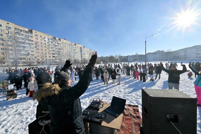 Residents dance during an outdoor DJ party in a one of a residential neighbourhood of Kyiv, to lift spirits during mass power outages and central heating on February 1, 2026 amid the Russian invasion of Ukraine. (Photo by Sergei SUPINSKY / AFP)