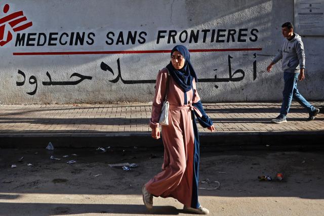 (FILES) Palestinians walk past the clinic of Doctors Without Borders or Medecins Sans Frontieres (MSF), in the al-Rimal neighborhood of Gaza City on January 11, 2026. Israel announced on February 1, 2026, it was terminating Doctors Without Borders' humanitarian operations in Gaza after the charity failed to provide a list of Palestinian staff, a move MSF said was a "pretext" to obstruct aid to the war-devastated territory. (Photo by Omar AL-QATTAA / AFP)