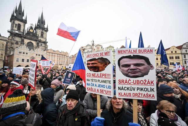 People hold a placard showing Czech Prime Minister Babis (L) during a demonstration in support of Czech President Petr Pavel at the Old Town Square in Prague on February  1, 2026. Tens of thousands of Czechs rallied in Prague on February 1 to support the country's pro-Ukrainian president, who is locked in a dispute with the government's nationalist billionaire leader Andrej Babis. Organisers from the independent Million Moments for Democracy movement claim up to 90,000 people attended the demonstration, where some participants waved Czech, European and Ukrainian flags. (Photo by Michal Cizek / AFP)