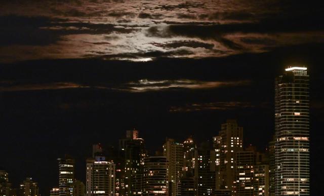 This view shows the skyline with the full moon in the background in Panama City on February 1, 2026. (Photo by MARTIN BERNETTI / AFP)