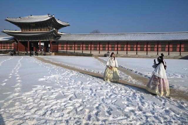 Visitors wearing traditional hanbok dresses pose for photos on the snow-covered grounds of Gyeongbokgung Palace in Seoul on February 2, 2026. (Photo by Jung Yeon-je / AFP)