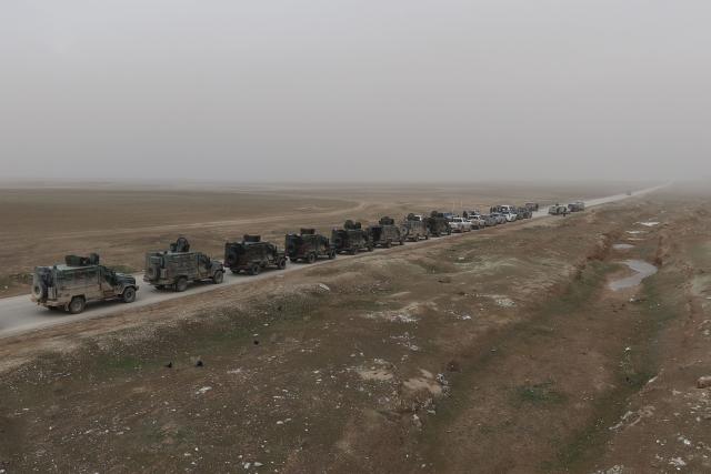 An aerial view shows a Syrian government forces military convoy driving along a road in the countryside near the northeastern Syrian city of Hasakeh on February 2, 2026. Northeast Syria's Hasakeh was under a curfew on February 2, 2026, as government forces were expected to enter parts of the city under an integration deal with the Kurds. Damascus and Kurdish forces reached a comprehensive agreement on Friday to gradually integrate the Kurds' military and civilian institutions into the state, after the minority ceded territory to advancing government forces in recent weeks. (Photo by Bakr ALKASEM / AFP)