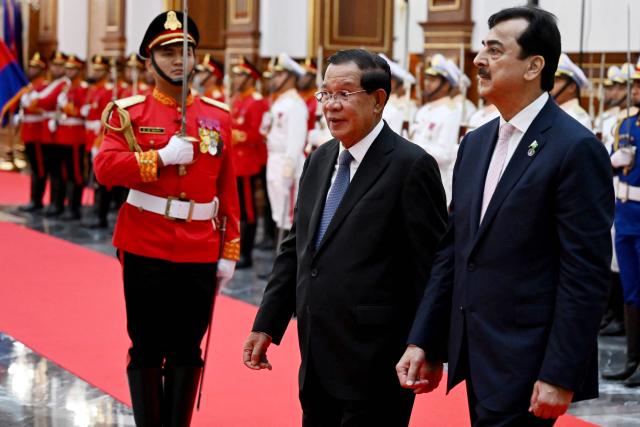 Cambodia's Senate President Hun Sen (C) and Pakistan's Senate Chairman Yusuf Raza Gilani (R) walk past an honour guard at the Senate building in Phnom Penh on February 2, 2026. (Photo by TANG CHHIN Sothy / AFP)