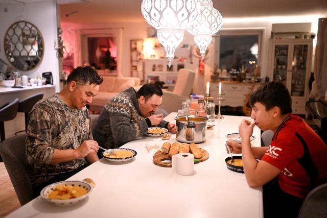 Hunter and fisherman Malik Kleist (C), Karl Joregn and his son eat a fish soup after an unsuccessful hunt for seals, at his home in Sisimiut, Greenland on February 1, 2026. Search for all these reportage images using: GREENLAND - DENMARK - HUNTING - SEALING. (Photo by Ina FASSBENDER / AFP)