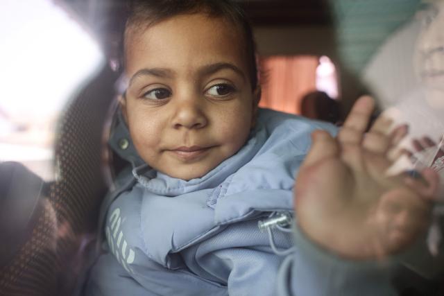 A Palestinians child waves from the window of a bus evacuating war-wounded and patients, accompanied by relatives, as they ready to leave the Gaza Strip for treatment abroad through the Rafah border crossing between Gaza and Egypt, the day after it was opened by Israel for a limited number of people, in Khan Yunis, in the southern Gaza Strip on February 2, 2026. Gaza's key Rafah border crossing reopened to Palestinians on February 2, an Israeli security official said, though Egyptian state-linked media said only 50 people would be allowed to cross in each direction in the early days. The resumption of operations comes after Gaza's civil defence reported dozens killed in a wave of Israeli strikes over the weekend, in what the military said was retaliation for Palestinian fighters exiting a tunnel in Rafah city. (Photo by Bashar Taleb / AFP)
