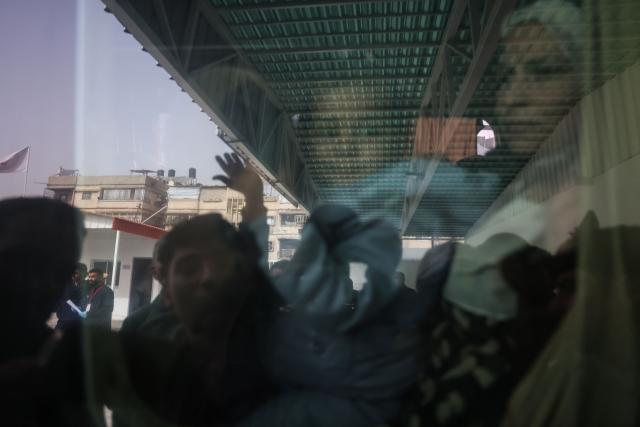 A Palestinians child waves from the window of a bus evacuating war-wounded and patients, accompanied by relatives, as they ready to leave the Gaza Strip for treatment abroad through the Rafah border crossing between Gaza and Egypt, the day after it was opened by Israel for a limited number of people, in Khan Yunis, in the southern Gaza Strip on February 2, 2026. Gaza's key Rafah border crossing reopened to Palestinians on February 2, an Israeli security official said, though Egyptian state-linked media said only 50 people would be allowed to cross in each direction in the early days. The resumption of operations comes after Gaza's civil defence reported dozens killed in a wave of Israeli strikes over the weekend, in what the military said was retaliation for Palestinian fighters exiting a tunnel in Rafah city. (Photo by Bashar Taleb / AFP)