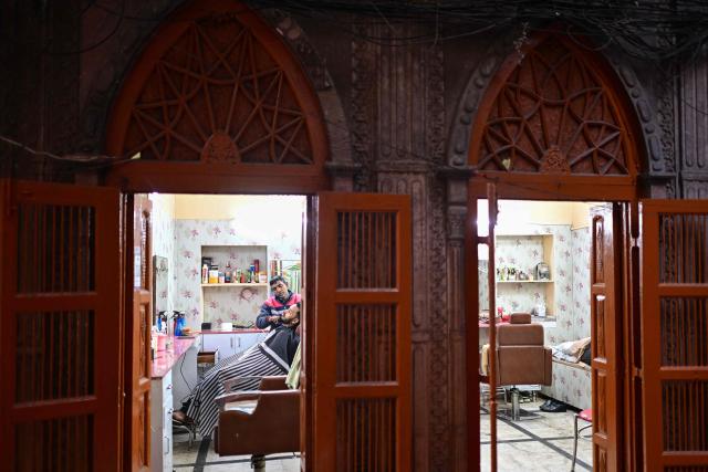 A barber tends to a customer at a salon in the old quarters of Delhi on February 2, 2026. (Photo by Manan VATSYAYANA / AFP)