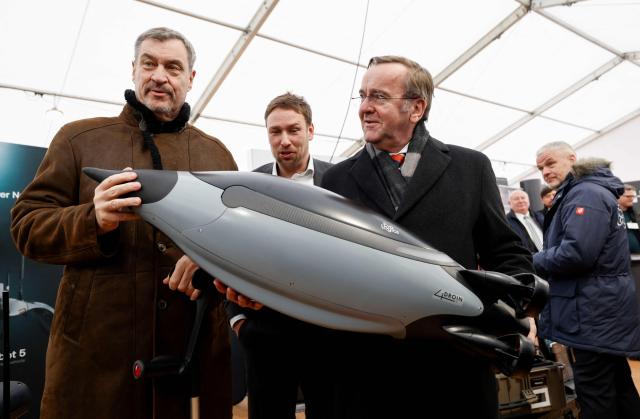 German Defence Minister Boris Pistorius (R) and Bavarian State Premier Markus Soeder (C) pose next to an Evo Logics Quadroin autonomous underwater vehicle  as they visit the Innovation Center of the German Armed Forces Bundeswehr in Erding, Bavaria, southern Germany on February 2, 2026, on the day of the center's inauguration. (Photo by Michaela Stache / AFP)