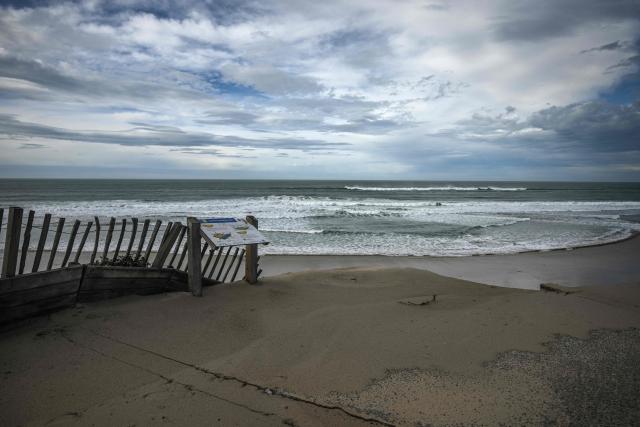 A wooden safety barrier stands at the edge of the collapsed Biscarrosse-Plage seafront promenade, with the Atlantic Ocean visible beyond, in south-western France, on February 1, 2026. Approximately 50 meters of the beachfront concrete walkway and public benches collapsed into the Atlantic Ocean, leaving a gap along the Atlantic coast resort's beachfront infrastructure. (Photo by Philippe LOPEZ / AFP)