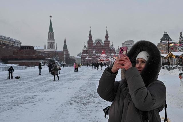 A woman takes pictures with a smartphone while visiting Red Square during a frosty day in central Moscow on February 2, 2026. (Photo by Hector RETAMAL / AFP)