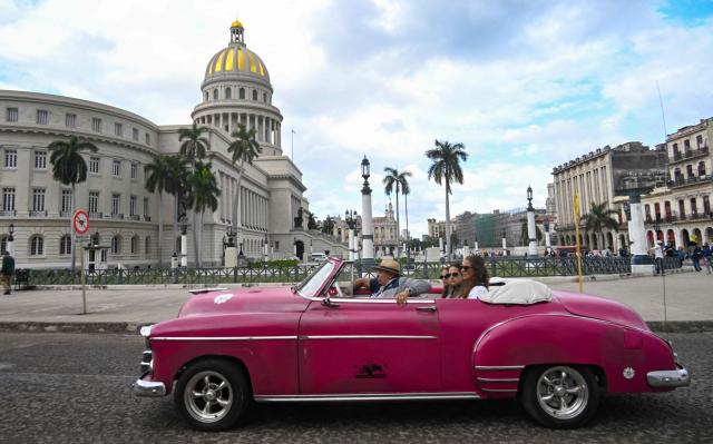 Tourists ride in an old American car used as a taxi in Havana on February 2, 2026. Tourism in Cuba suffered a sharp setback in 2025. The country ended the year with 1.8 million visitors, a 17.8 percent drop from 2024 and far below the official target of 2.6 million, according to data published on February 1 by the National Office of Statistics and Information (ONEI), which described the period as "terrible" for one of the key sectors of the economy. (Photo by YAMIL LAGE / AFP)