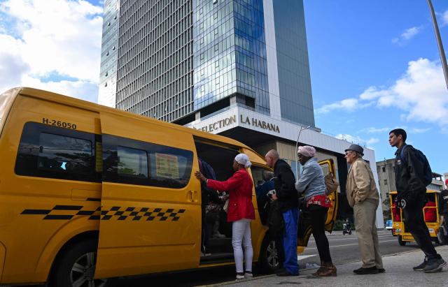 Cubans queue to board a public-transport minibus near the Iberostar Selection La Habana Hotel in Havana on February 2, 2026. Tourism in Cuba suffered a sharp setback in 2025. The country ended the year with 1.8 million visitors, a 17.8 percent drop from 2024 and far below the official target of 2.6 million, according to data published on February 1 by the National Office of Statistics and Information (ONEI), which described the period as "terrible" for one of the key sectors of the economy. (Photo by YAMIL LAGE / AFP)