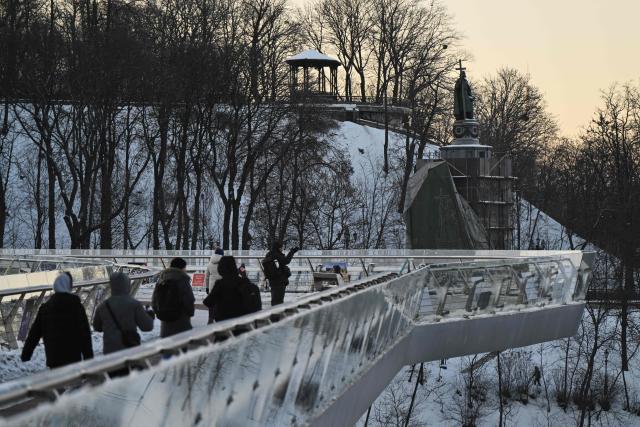 People walk across a bridge on a cold winter day through a snow-covered park in central Kyiv on February 2, 2026, amid the Russian invasion of Ukraine. The Ukrainian Hydrometeorological Center reported that from February 1 to 3, nighttime temperatures in some regions of the country could drop to minus 27 °C. (Photo by Genya SAVILOV / AFP)