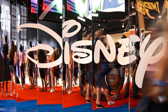 (FILES) Attendees are reflected in Disney+ logo during the Walt Disney D23 Expo in Anaheim, California on September 9, 2022. The Walt Disney Company on February 2, 2026 reported quarterly earnings showing that streaming services gained momentum and theme-park revenue hit record levels, but the company warned of a possible slowdown in the United States. Net profit reached $2.48 billion, down 6 percent year-over-year, according to a statement, with the Experiences division -- Disney's theme parks and resorts -- delivering record quarterly revenue of $10.0 billion. (Photo by Patrick T. FALLON / AFP)
