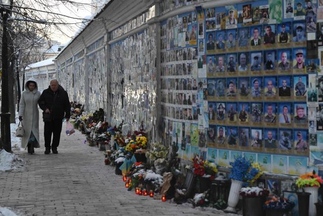 People walk past The Wall of Remembrance of the Fallen for Ukraine, a memorial for Ukrainian soldiers, on a cold winter day in Kyiv on February 2, 2026, amid the Russian invasion of Ukraine. The Ukrainian Hydrometeorological Center reported that from February 1 to 3, nighttime temperatures in some regions of the country could drop to minus 27 °C. (Photo by Genya SAVILOV / AFP)