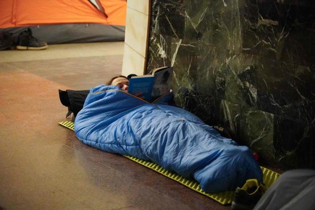 A woman reads a book as she takes shelter at a metro station during a Russian air attack, in Kyiv, on early February 3, 2026, amid the Russian invasion of Ukraine. (Photo by Serhii Okunev / AFP)
