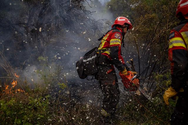 A firefighter works to extinguish a forest fire burning in the mountains of the rural area of Epuyen, in the Patagonian region of Chubut province, Argentina on February 2, 2026. Argentina's government on January 29, 2026, declared an emergency in Patagonia, where wildfires have ripped through vast tracts of forest since the start of the Southern Hemisphere summer. (Photo by TOMAS CUESTA / AFP)