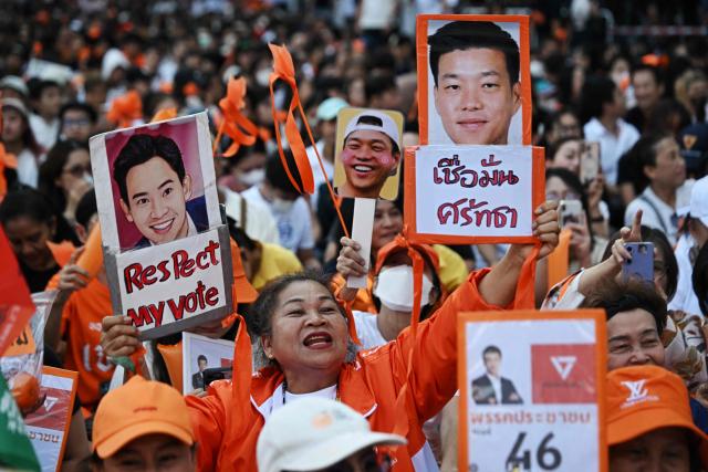 (FILES) A People's Party supporter holds signs with party leader and prime ministerial candidate Natthaphong Ruengpanyawut (R) and former Thai prime ministerial candidate and ex Move Forward Party leader Pita Limjaroenrat (L) at a People's Party rally ahead of the general election in Bangkok on January 25, 2026. Thousands of young orange-clad supporters cheered the rallies of Thailand's most popular political party ahead of elections on February 8, but few expect it to take power. While the People's Party is far ahead in the polls, promising to tackle corruption and reform Thailand's strict royal insult laws, even some of the party's lawmakers have their doubts. (Photo by Lillian SUWANRUMPHA / AFP)
