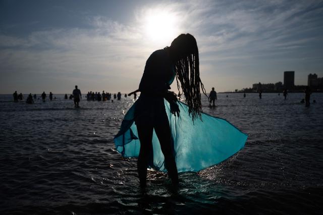 A believer offers tribute to Iemanja, the Goddess of the Sea of the Afro-American religion Umbanda, at Ramirez Beach in Montevideo on February 2, 2026. (Photo by Eitan ABRAMOVICH / AFP)
